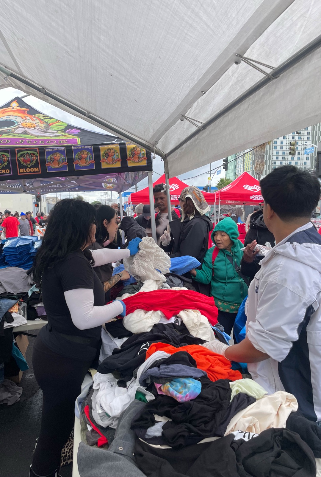 Volunteers handing out clothing from a table under a canopy on Skid Row